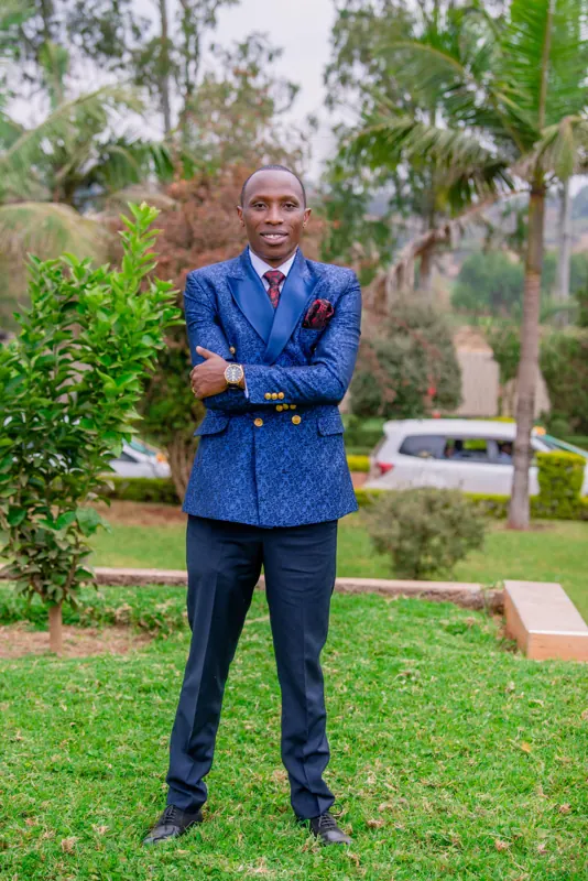 Simon Mugetha in a blue double-breasted suit, standing in a garden