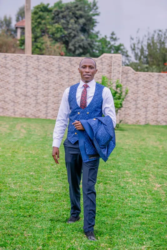 Simon Mugetha walking across a lawn with his jacket over his arm
